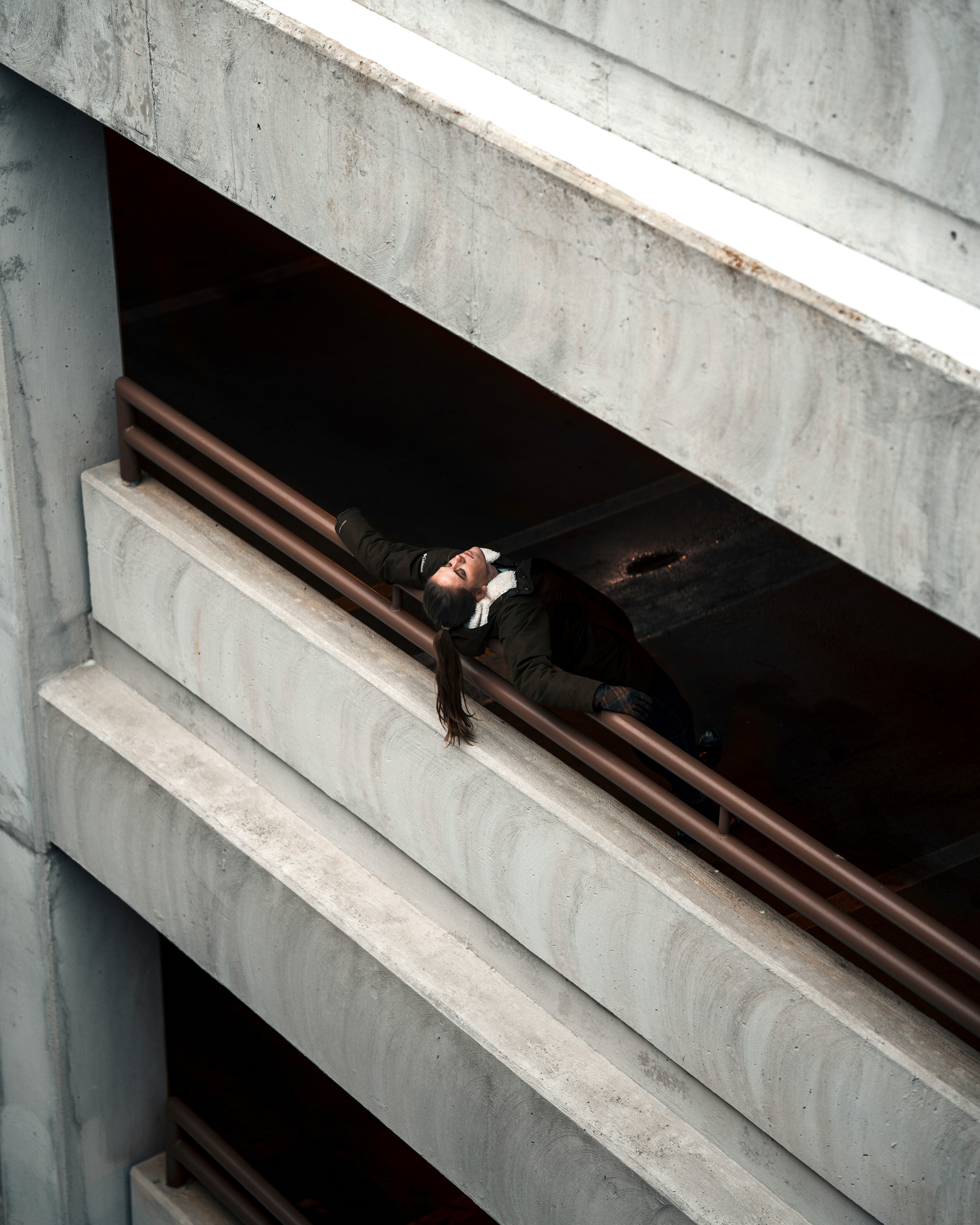 man in black jacket and black pants sitting on white concrete staircase